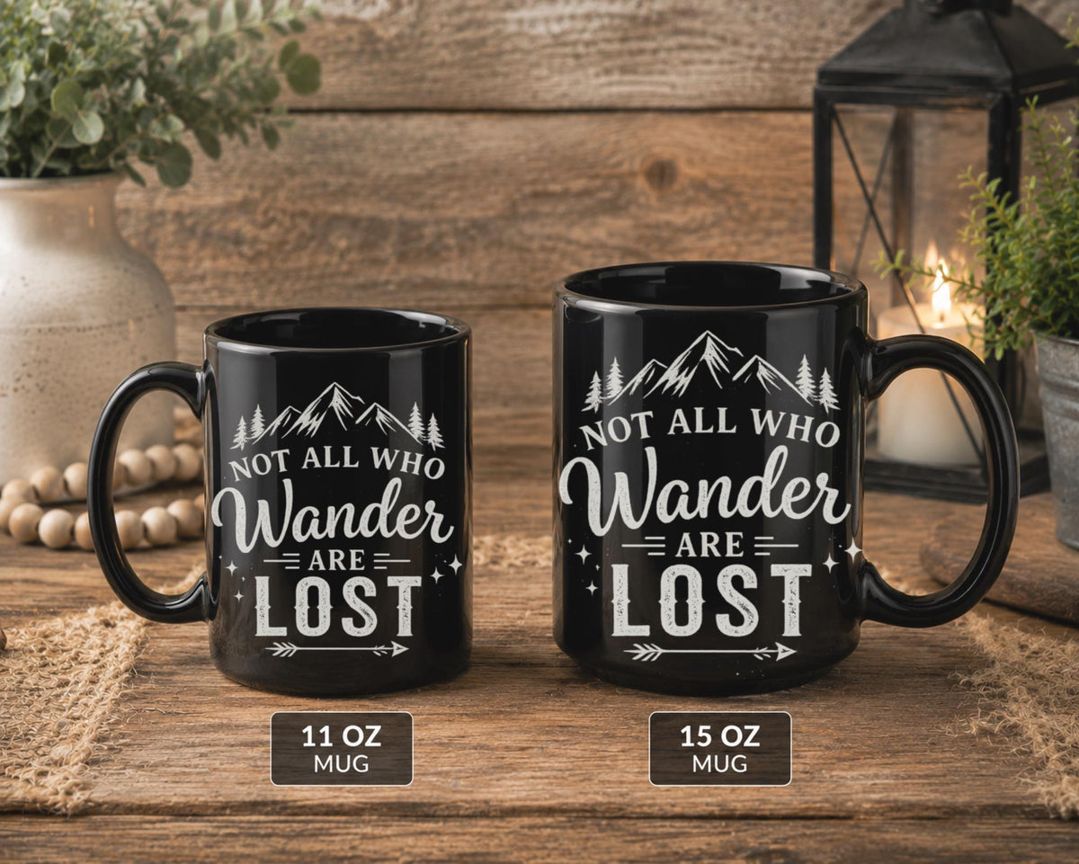 A side by side of the Black ceramic mugs available in 11oz or 15oz,  featuring mountain artwork and the phrase "Not All Who Wander Are Lost" displayed in white typography on a cozy rustic background.