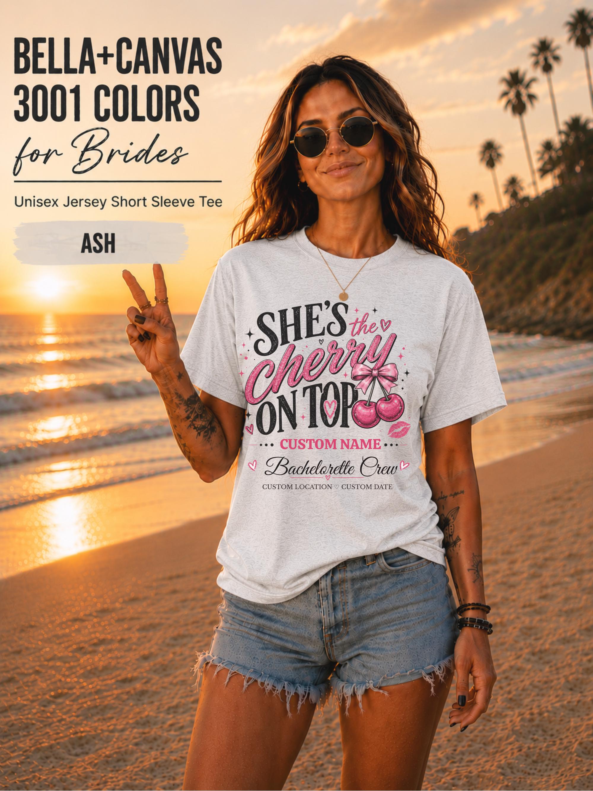 Bella+Canvas 3001 Ash unisex T-shirt featuring a customizable "She's the Cherry on Top" bachelorette crew design with pink cherries, custom name, location, and wedding date for bridal party celebrations.