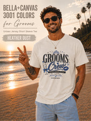 Bella+Canvas 3001 Heather Dust groom crew shirt featuring a blue wedding party design with champagne glass, crown, kiss mark, and customizable wedding date for bachelor party celebrations.