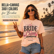 Bella+Canvas 3001 Heather Prism Peach bride crew shirt featuring a pink and black bachelorette design with champagne glass, crown, kiss mark, and customizable wedding date.