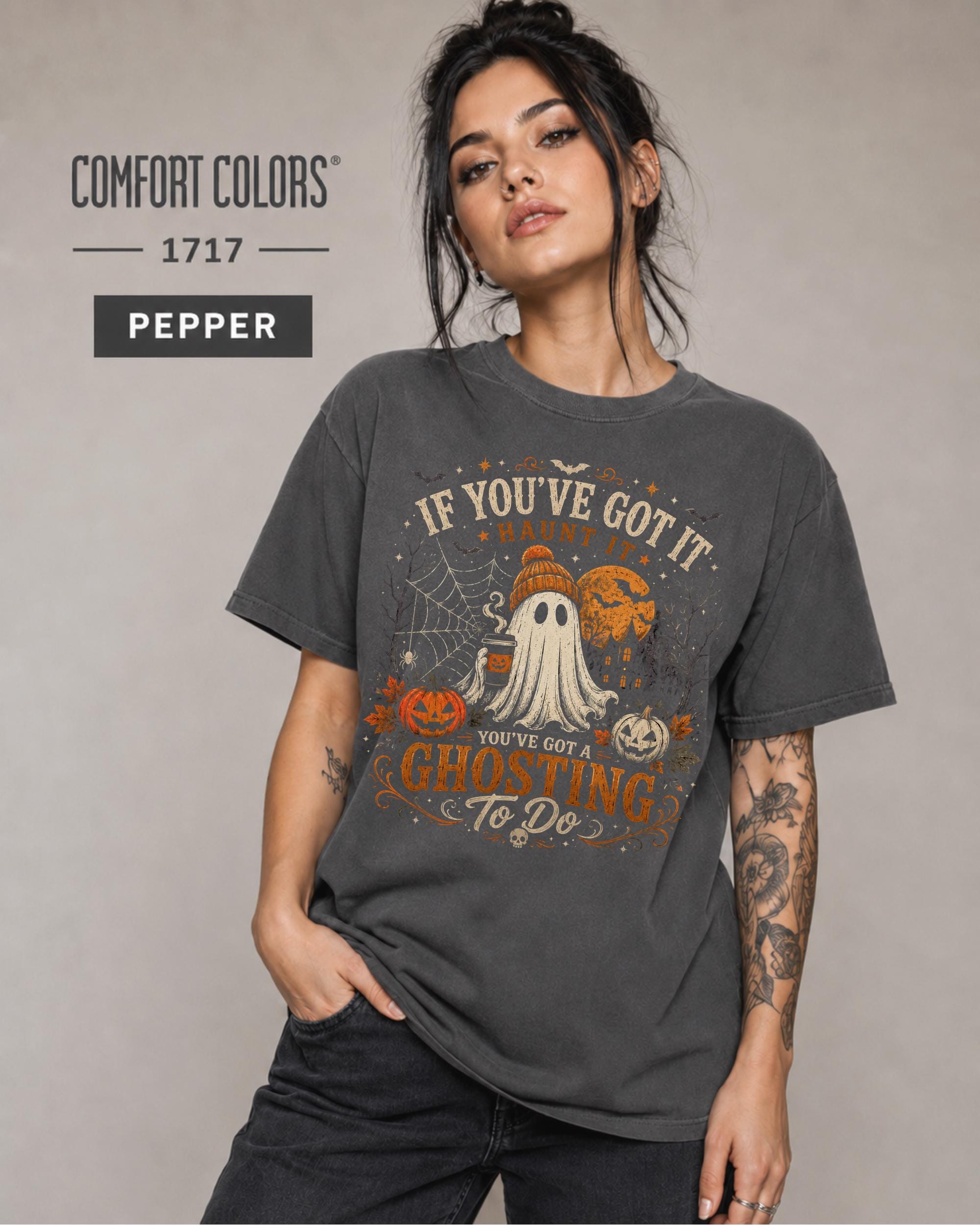 Woman wearing a Comfort Colors 1717 Pepper T-shirt featuring a vintage Halloween ghost design with pumpkins, spiderwebs, haunted house, moon, bats, and the funny quote "If You've Got It Haunt It... You've Got a Ghosting To Do."