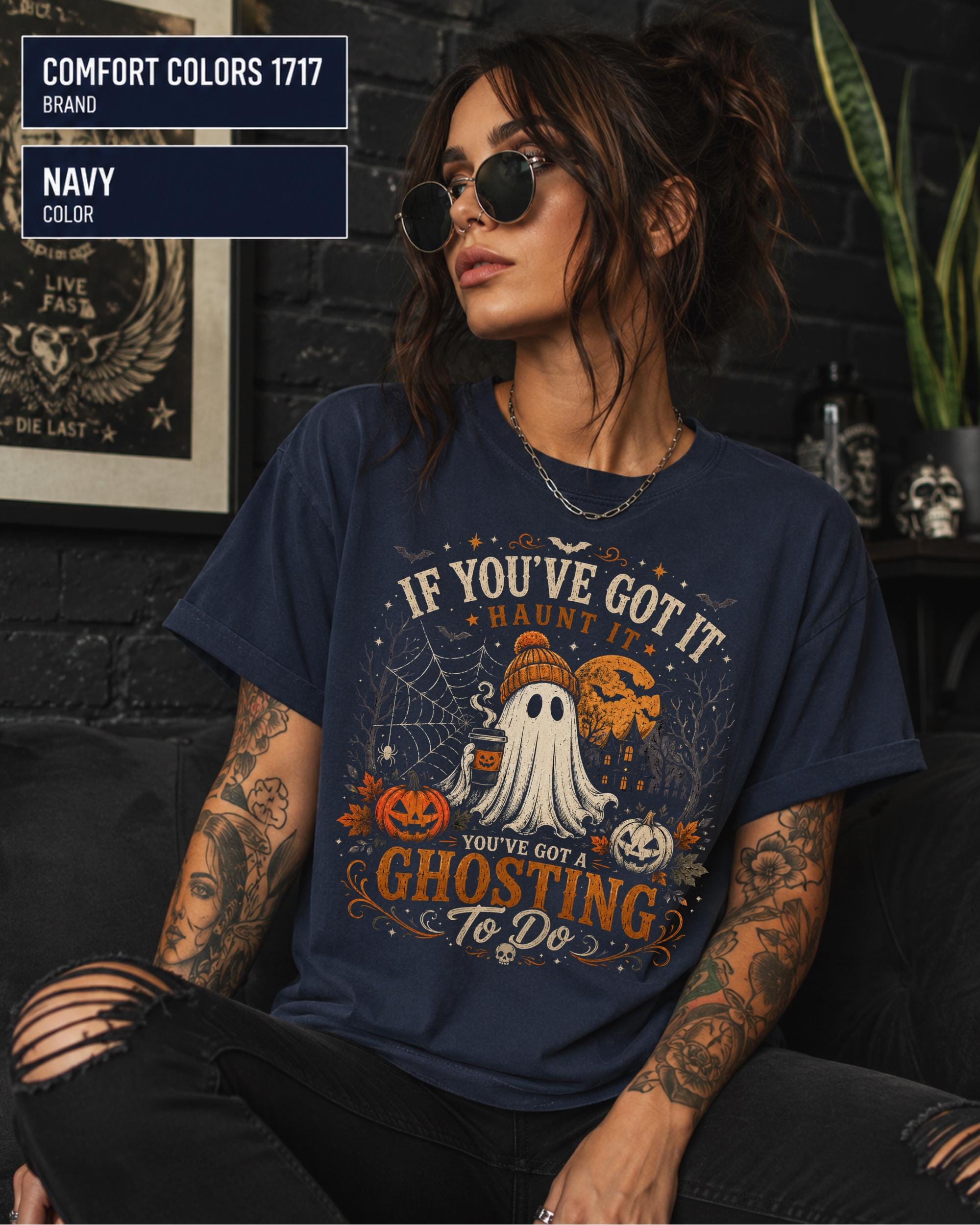 Woman wearing a Comfort Colors 1717 Navy T-shirt featuring a vintage Halloween ghost design with pumpkins, spiderwebs, haunted house, moon, bats, and the funny quote "If You've Got It Haunt It... You've Got a Ghosting To Do."