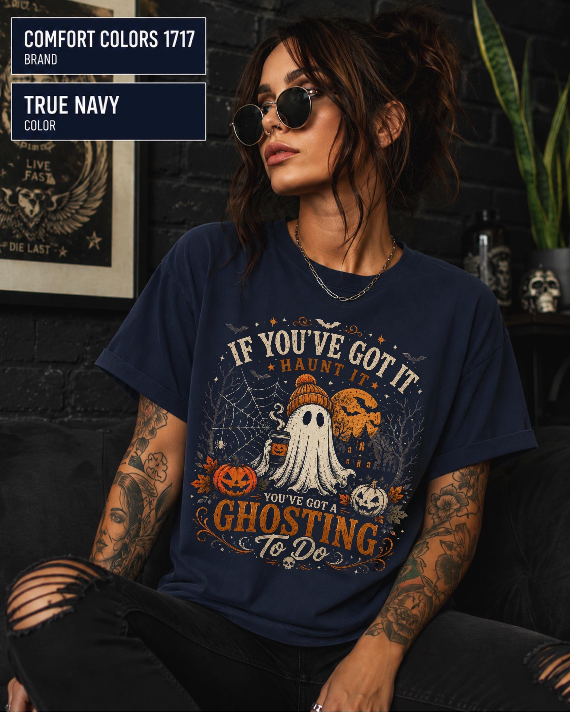 Woman wearing a Comfort Colors 1717 True Navy T-shirt featuring a vintage Halloween ghost design with pumpkins, spiderwebs, haunted house, moon, bats, and the funny quote "If You've Got It Haunt It... You've Got a Ghosting To Do."