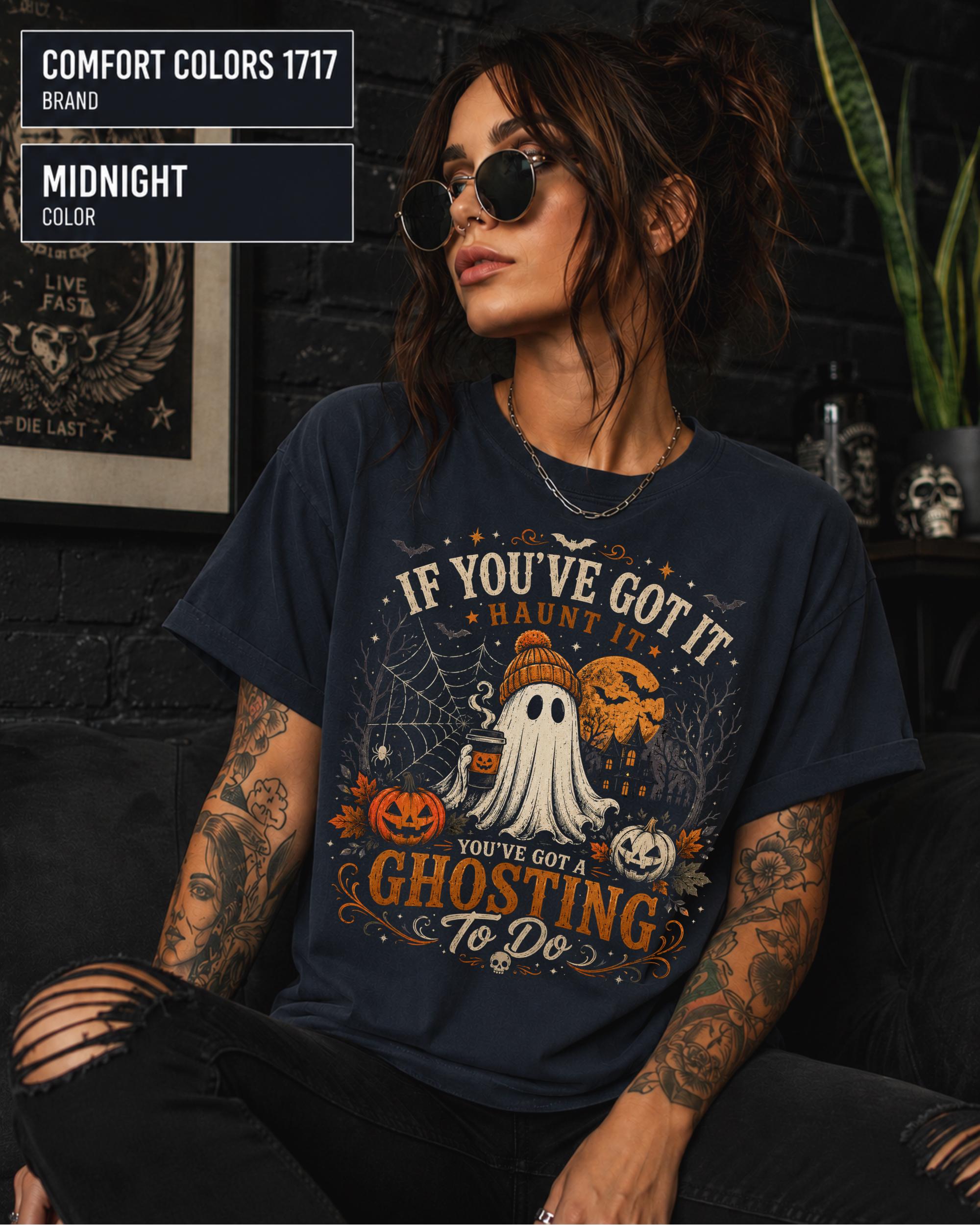 Woman wearing a Comfort Colors 1717 Midnight T-shirt featuring a vintage Halloween ghost design with pumpkins, spiderwebs, haunted house, moon, bats, and the funny quote "If You've Got It Haunt It... You've Got a Ghosting To Do."