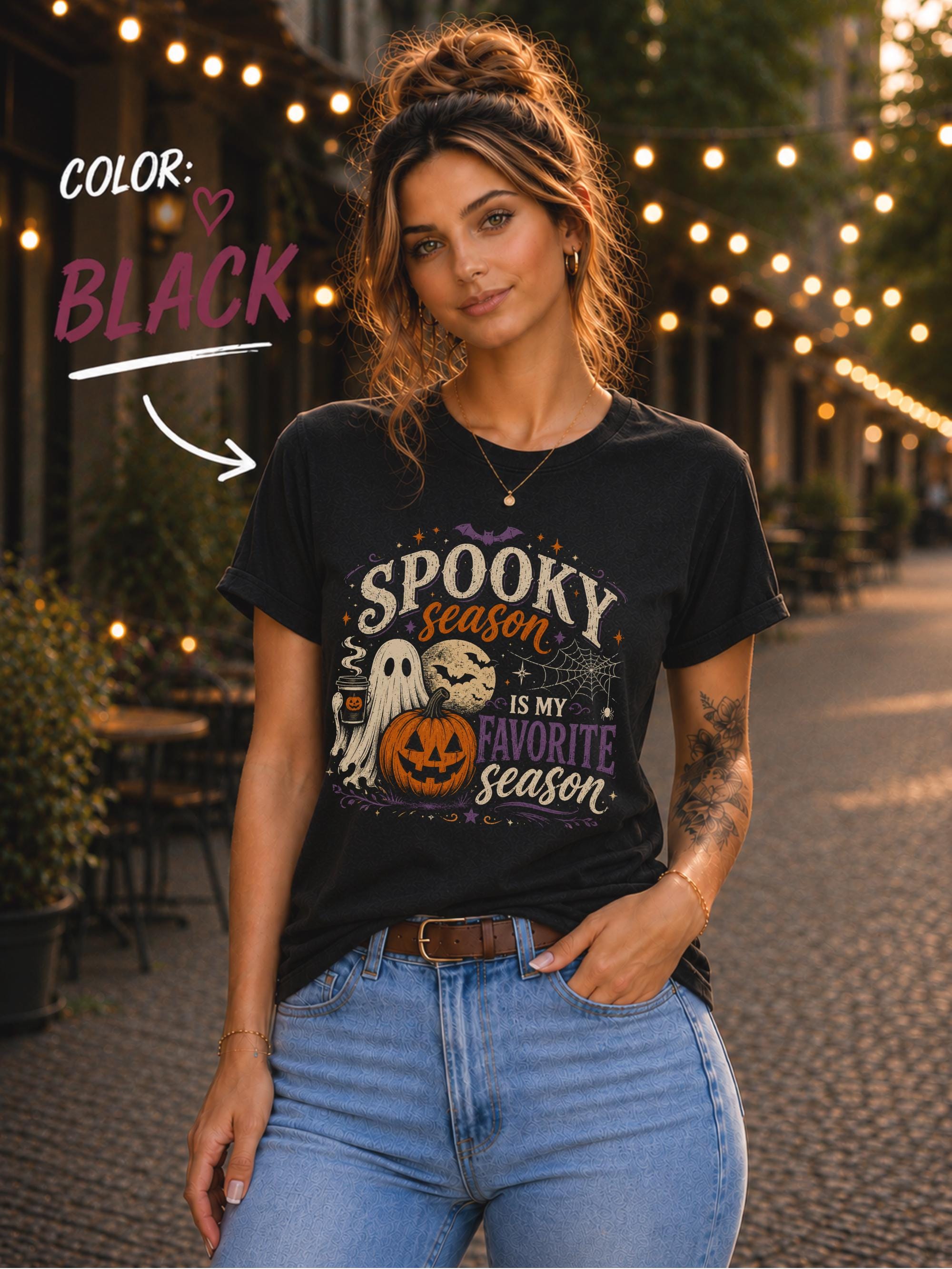 Woman wearing a Bella+Canvas 3001 Black unisex T-shirt featuring a vintage Halloween design with a cute ghost, pumpkin, spiderweb, full moon, and the phrase "Spooky Season Is My Favorite Season."
