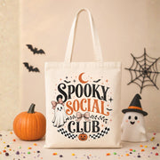 Natural canvas tote bag featuring a vintage Spooky Social Club design with a cute ghost, bows, bats, moon, pumpkin, and retro Halloween typography, perfect for everyday fall use and Halloween shopping.