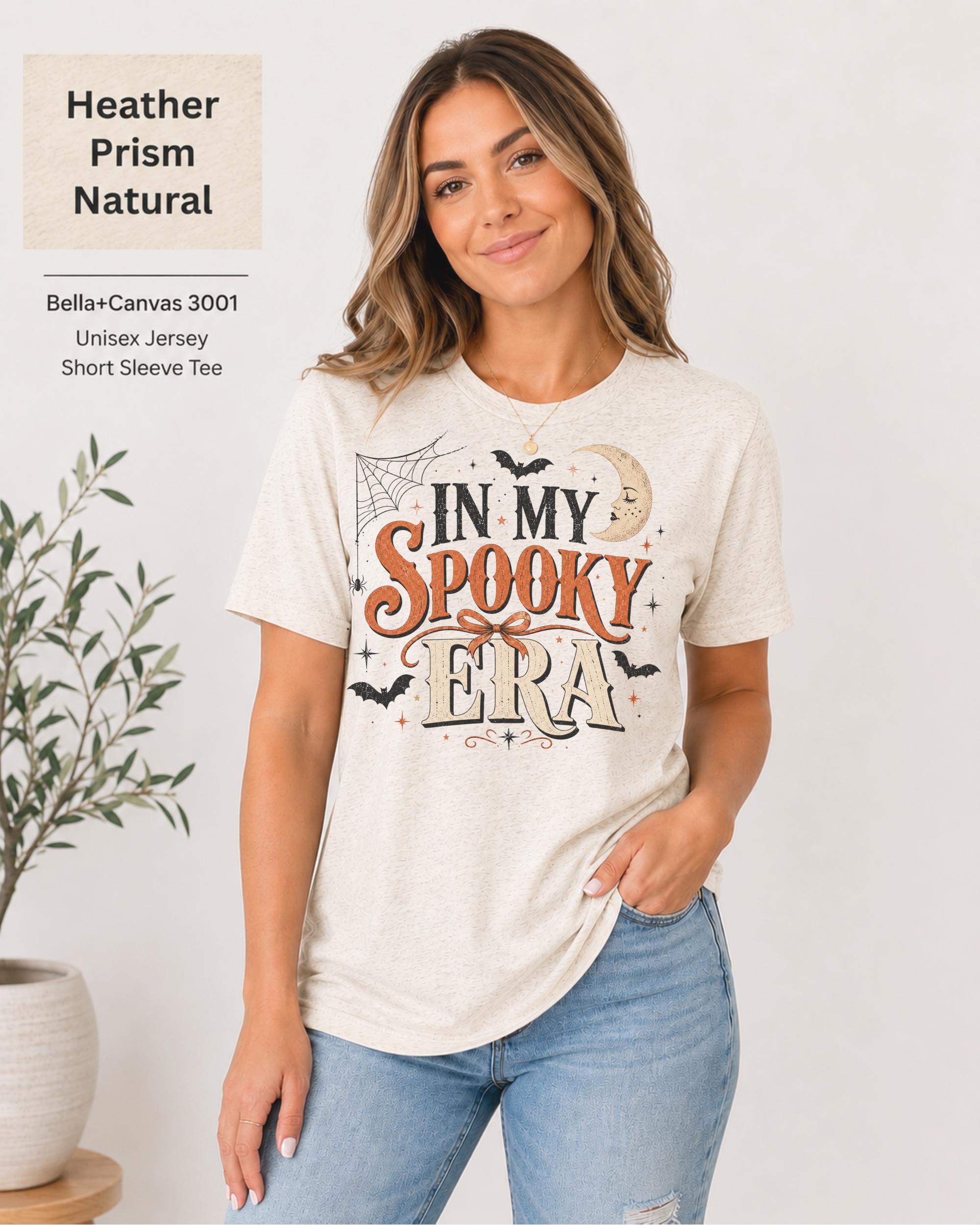Bella+Canvas 3001 Heather Prism Natural unisex t-shirt featuring an "In My Spooky Era" Halloween graphic with vintage lettering, bats, crescent moon, spiderweb, and autumn-inspired artwork.