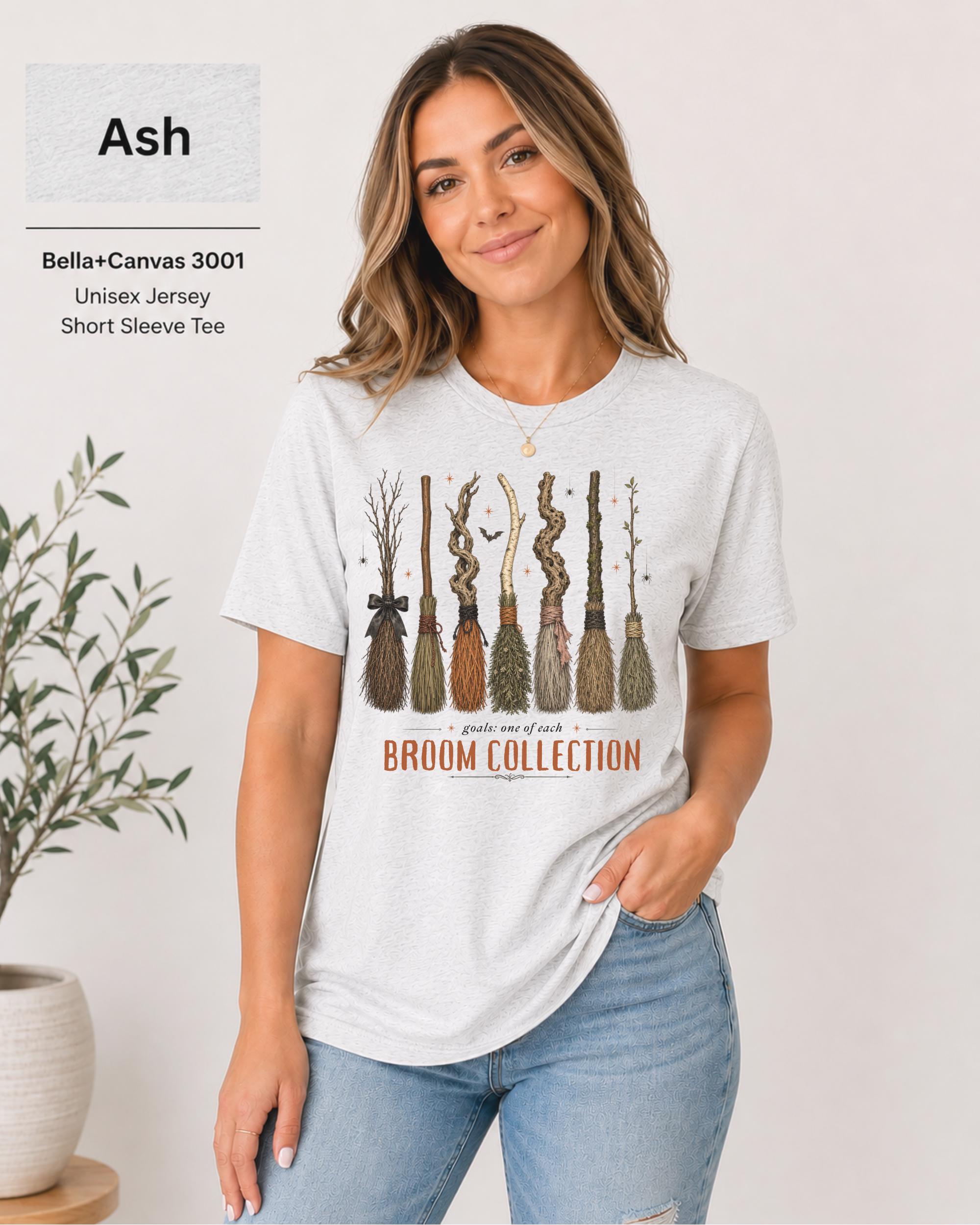 Bella+Canvas 3001 Ash unisex t-shirt featuring a vintage Broom Collection graphic with illustrated witch brooms, earthy autumn colors, and cozy Halloween-inspired artwork.