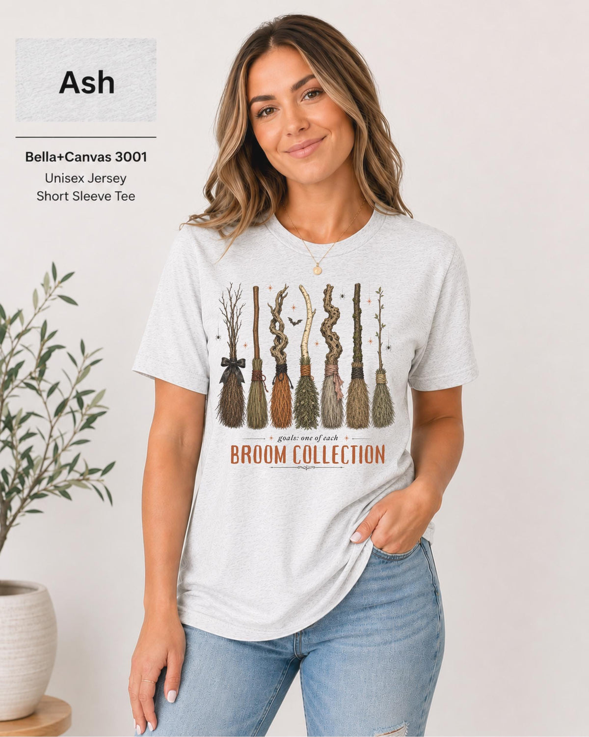 Bella+Canvas 3001 Ash unisex t-shirt featuring a vintage Broom Collection graphic with illustrated witch brooms, earthy autumn colors, and cozy Halloween-inspired artwork.