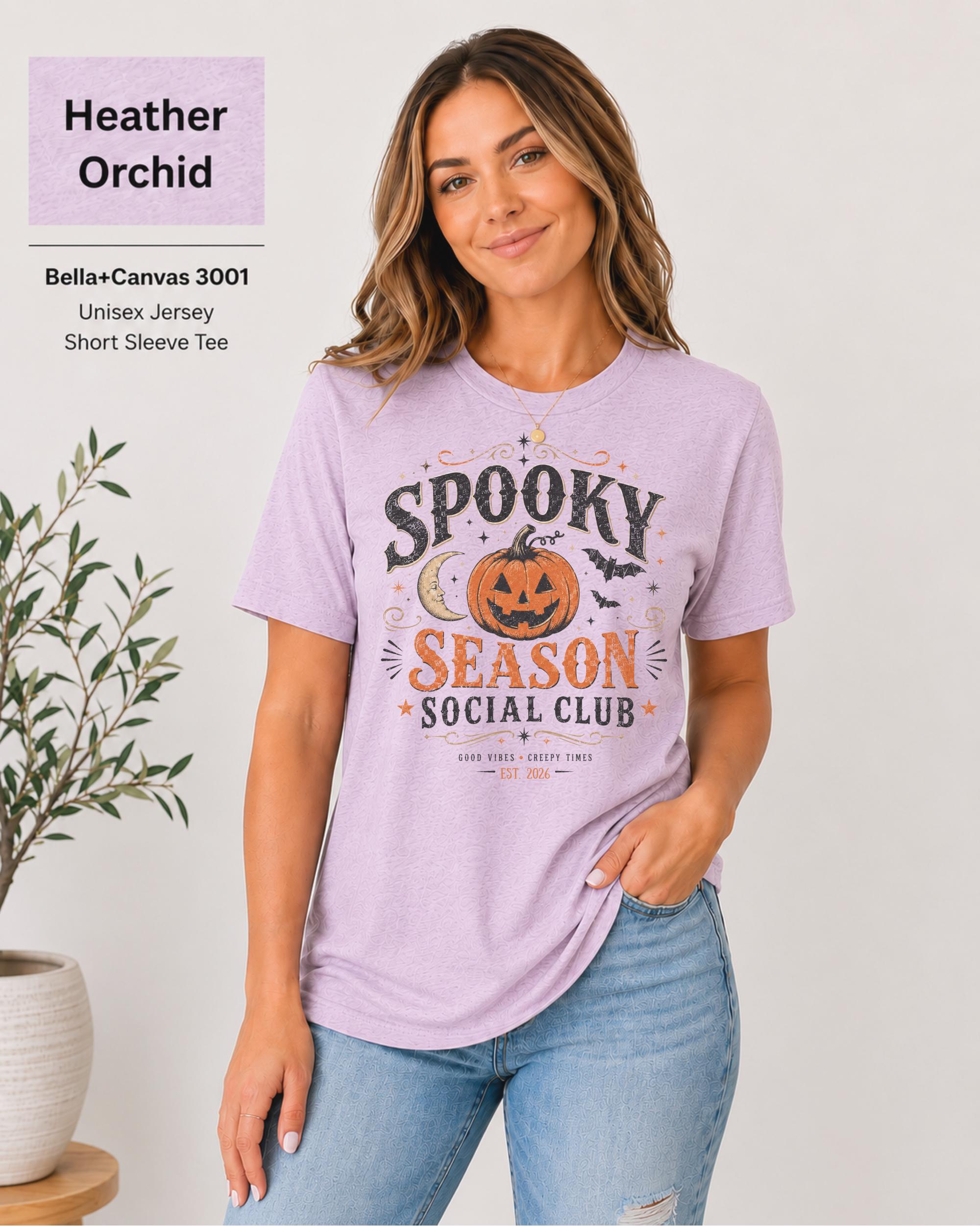 Bella+Canvas 3001 Heather Orchid unisex t-shirt featuring a vintage "Spooky Season Social Club" graphic with a smiling pumpkin, crescent moon, bats, and distressed autumn typography for Halloween and fall.