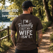 Funny husband t-shirt with "I'm Friendly But My Wife Isn't" back print on a Dark Chocolate Gildan 5000 unisex tee, humorous men's graphic shirt for husbands, dads, and Father's Day gifts.