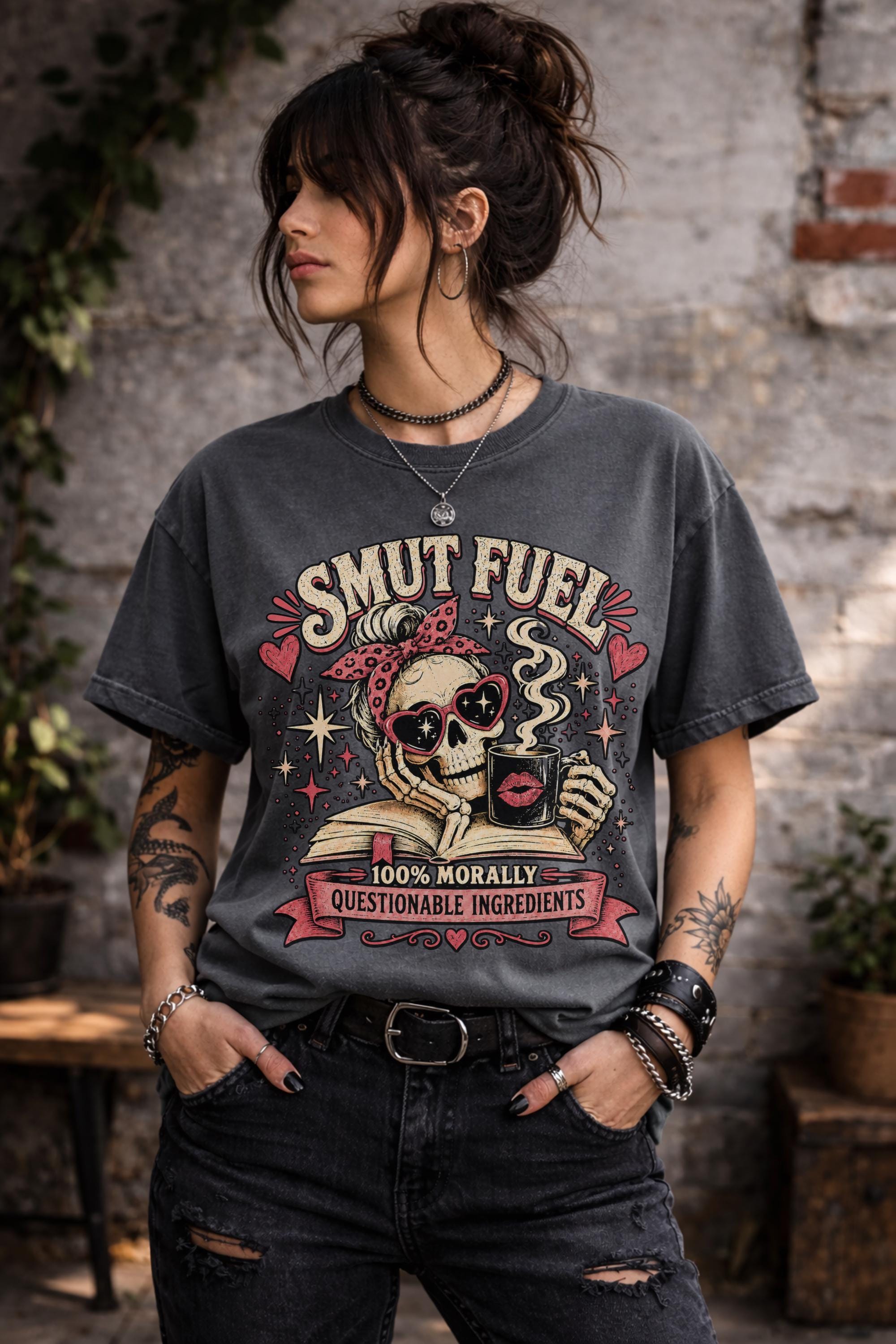 Smut Fuel graphic tee featuring a skeleton reader with a coffee mug and dark romance theme