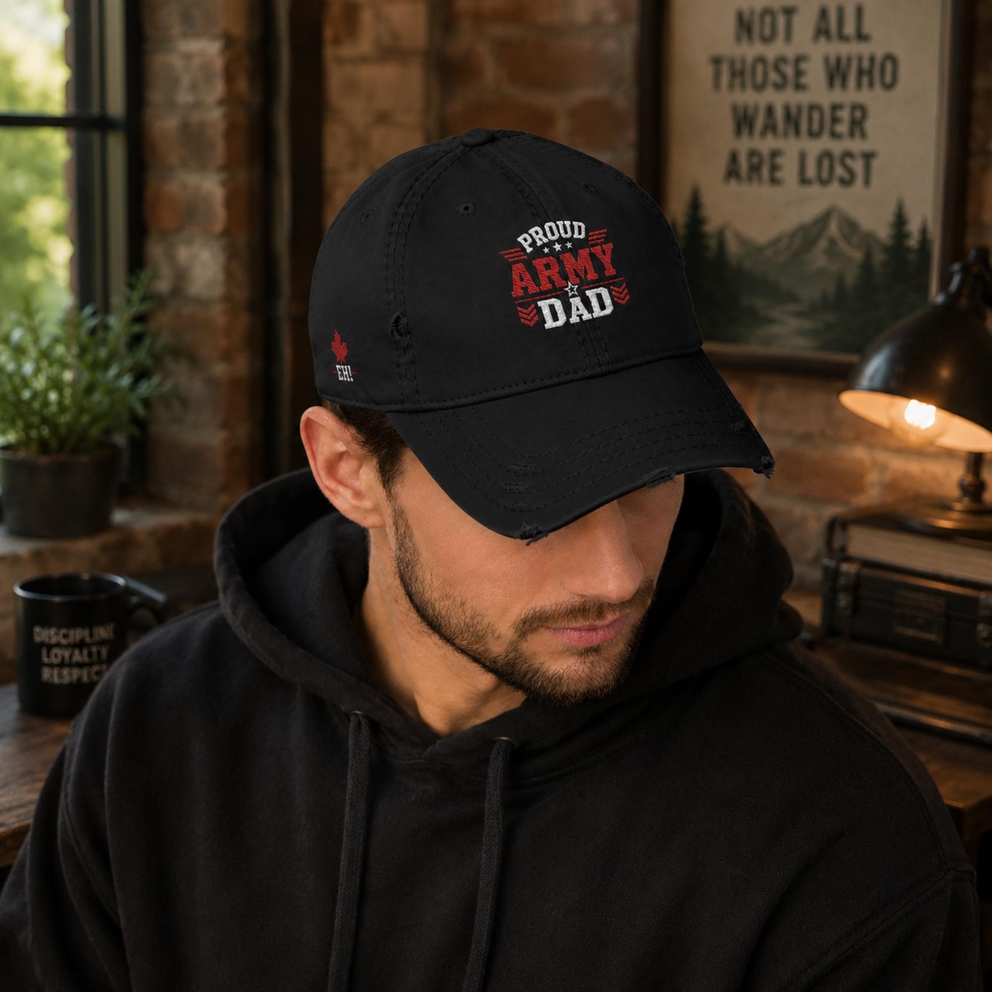 Black distressed embroidered dad hat featuring a bold "Proud Army Dad" design on the front with a red maple leaf and "EH!" embroidery on the side, styled in a rustic outdoor setting with camping accessories.