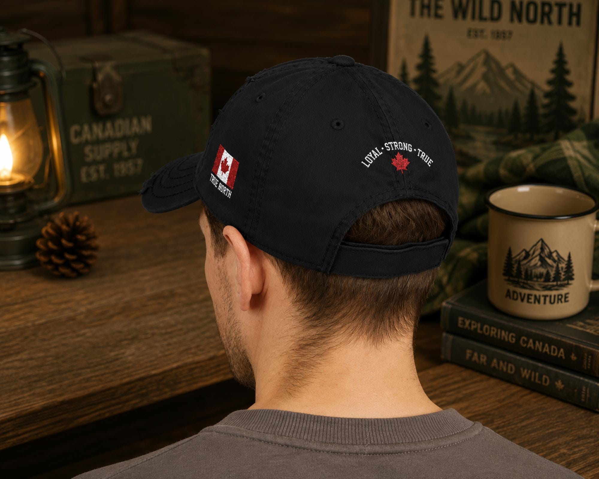 Black distressed embroidered dad hat featuring "Proud Canadian Strong & Free" on the front with maple leaf accents, Canadian flag embroidery on the side, and an EH! maple leaf detail in a rustic outdoor setting.