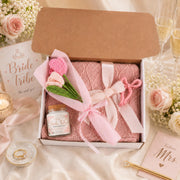 Personalized bridesmaid proposal gift box featuring a Bride Tribe candle, blush pink blanket, crochet flowers, and pink bow hair clip.