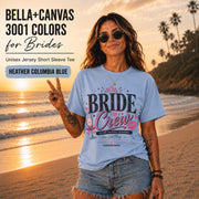 Bella+Canvas 3001 Heather Columbia Blue bride crew shirt featuring a pink and black bachelorette design with champagne glass, crown, kiss mark, and customizable wedding date.