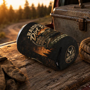 Regular can cooler with "Raised on Dirt Roads" vintage truck design displayed on a rustic wooden tailgate beside work gloves and rope at sunset, ideal for country, camping, and outdoor enthusiasts.