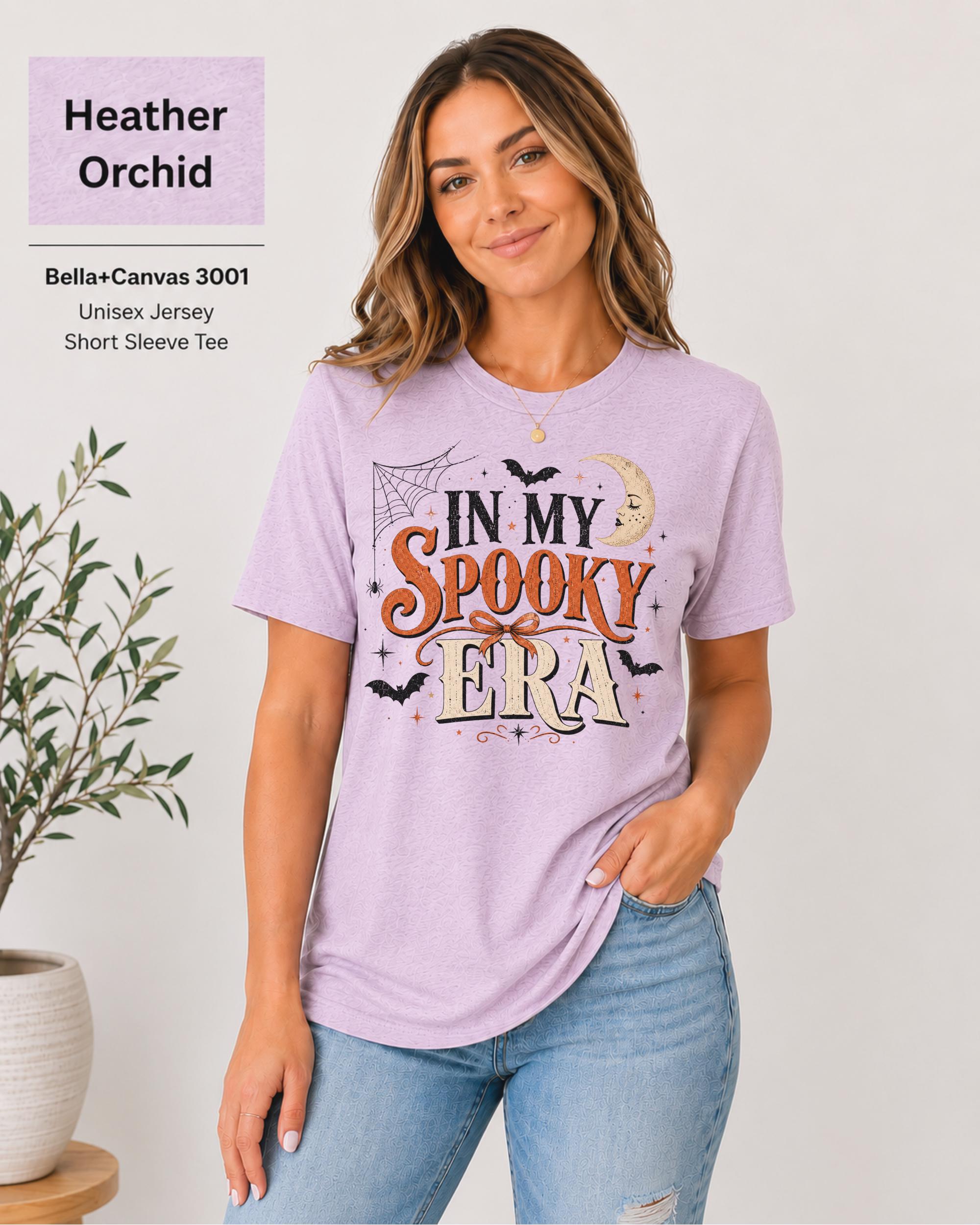Bella+Canvas 3001 Heather Orchid unisex t-shirt featuring an "In My Spooky Era" Halloween graphic with vintage lettering, bats, crescent moon, spiderweb, and autumn-inspired artwork.