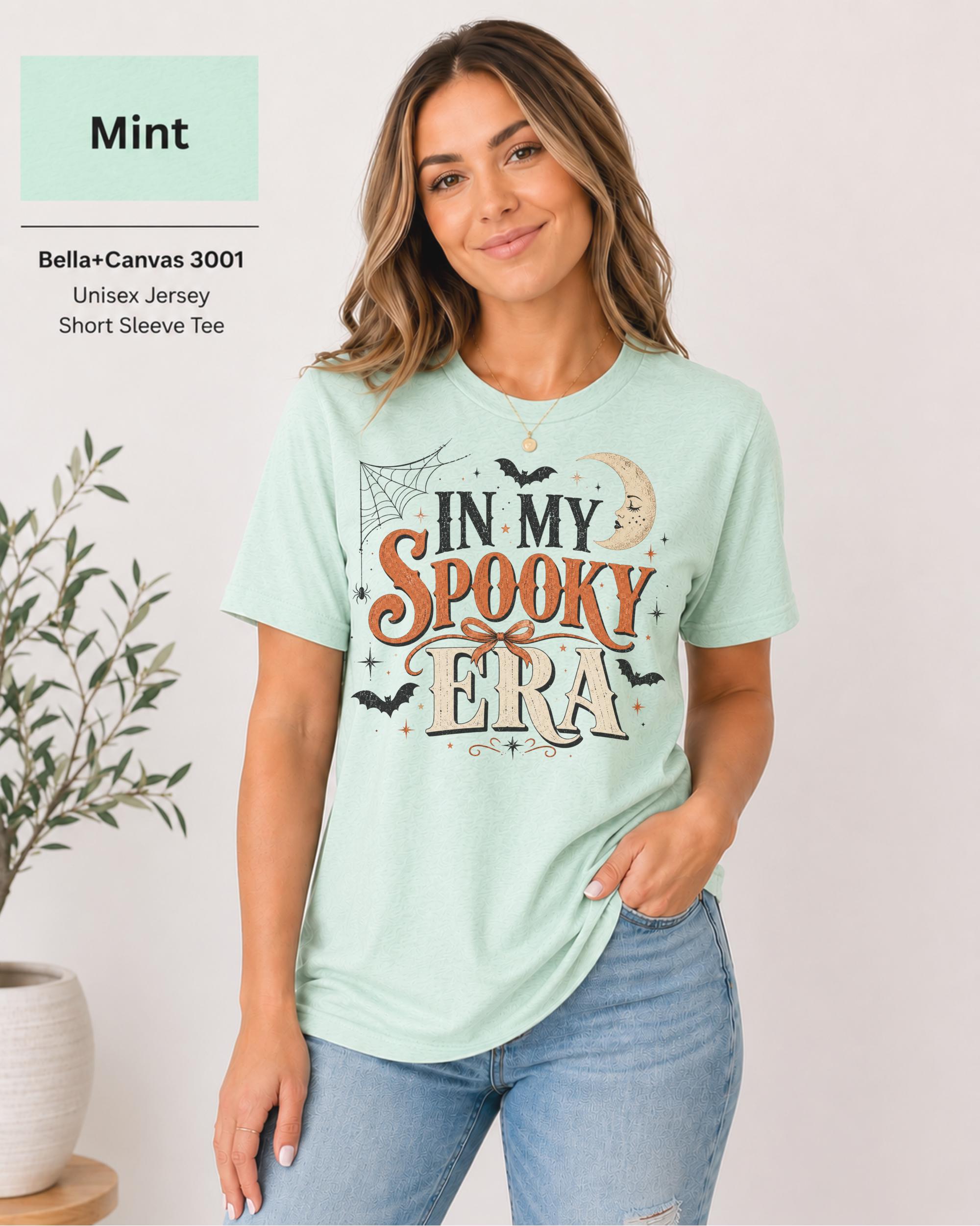 Bella+Canvas 3001 Mint unisex t-shirt featuring an "In My Spooky Era" Halloween graphic with vintage lettering, bats, crescent moon, spiderweb, and autumn-inspired artwork.