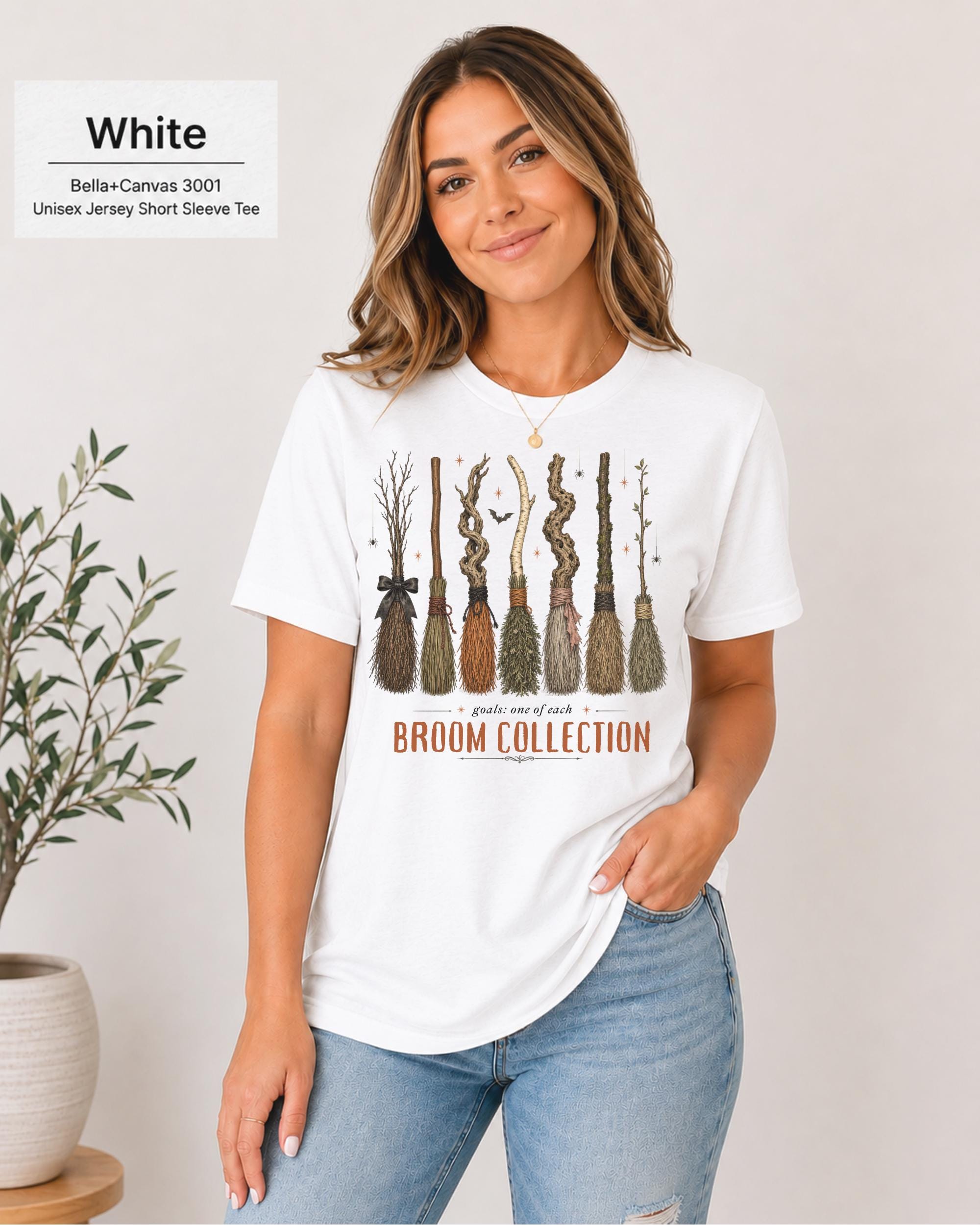 Bella+Canvas 3001 White unisex t-shirt featuring a vintage Broom Collection graphic with illustrated witch brooms, earthy autumn colors, and cozy Halloween-inspired artwork.