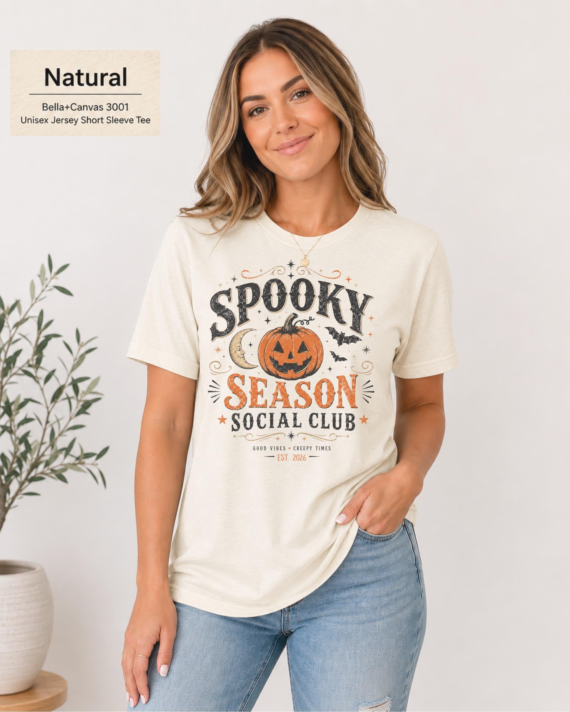 Bella+Canvas 3001 Natural unisex t-shirt featuring a vintage "Spooky Season Social Club" graphic with a smiling pumpkin, crescent moon, bats, and distressed autumn typography for Halloween and fall.