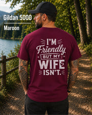 Funny husband t-shirt with "I'm Friendly But My Wife Isn't" back print on a maroon Gildan 5000 unisex tee, humorous men's graphic shirt for husbands, dads, and Father's Day gifts.