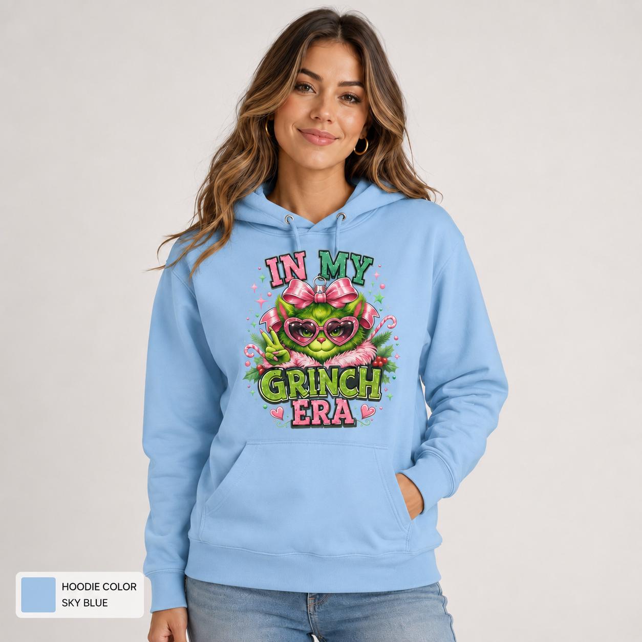 Female model wearing a sky blue hoodie with a colorful Christmas character, pink bow, candy canes, and holiday text.