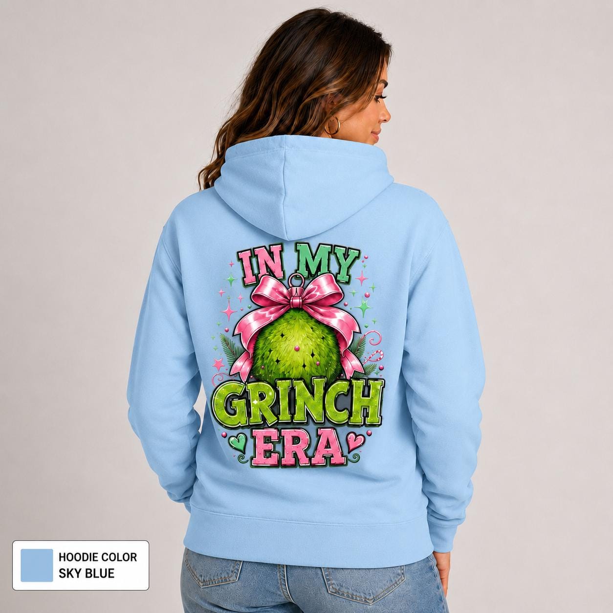 Back view of sky blue hoodie with an oversized green ornament design, pink bow, hearts, and In My Grinch Era lettering.