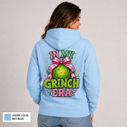Back view of sky blue hoodie with an oversized green ornament design, pink bow, hearts, and In My Grinch Era lettering.