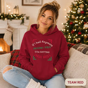 Female model wearing a team red Christmas hoodie reading “If I had anymore Christmas spirit, I’d be shitting jingle bells” in a cozy holiday room.