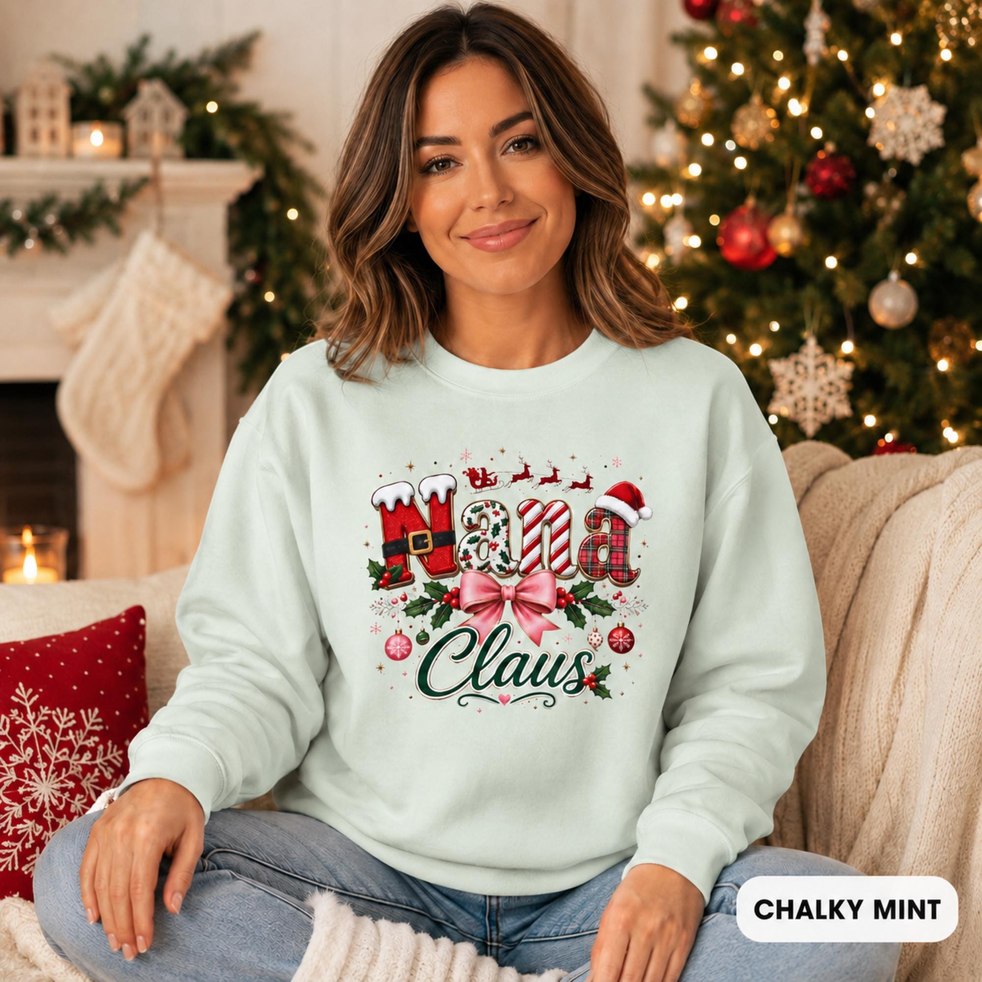 Female model wearing an chalky mint Comfort Colors crewneck featuring a festive “Nana Claus” Christmas design with a pink bow, holly, ornaments, and holiday lettering.