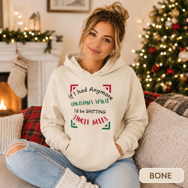 Female model wearing a bone Christmas hoodie reading “If I had anymore Christmas spirit, I’d be shitting jingle bells” in a cozy holiday room.