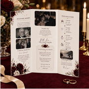 Folded wedding ceremony brochure standing on burgundy velvet beside candles, wedding rings and burgundy floral arrangements.
