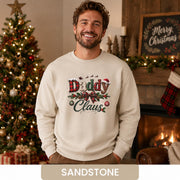 Man wearing a sandstone Daddy Claus Christmas sweatshirt with plaid lettering, festive bow, holly, and ornaments.