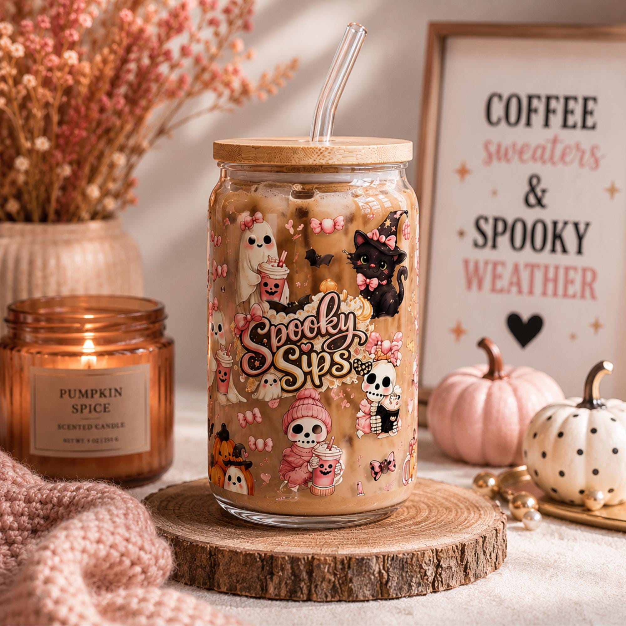 16oz Halloween glass tumbler with cute ghost and pumpkin artwork styled with cozy autumn decor and seasonal accessories.