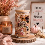 16oz Halloween glass tumbler with cute ghost and pumpkin artwork styled with cozy autumn decor and seasonal accessories.