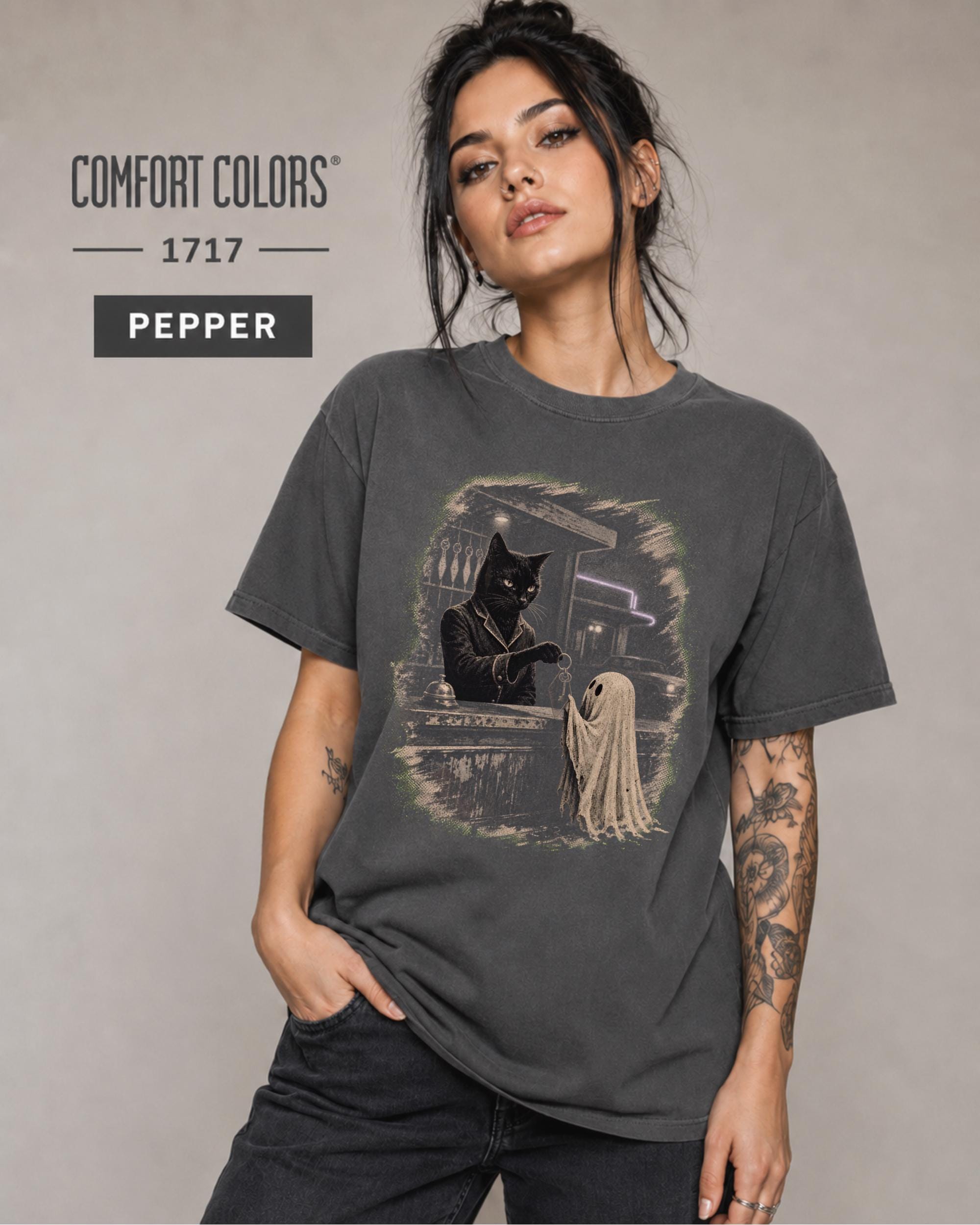 Woman wearing a Pepper Comfort Colors 1717 shirt featuring a black cat hotel clerk and small ghost.
