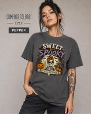 Woman wearing a Pepper Comfort Colors 1717 shirt featuring a Sweet but Spooky skeleton Halloween design.