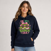 Front view of navy blue hoodie displaying a large In My Grinch Era holiday ornament design with pink and green details.