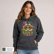 Female model wearing a carbon grey hoodie with a vibrant pink and green holiday design and color label shown.