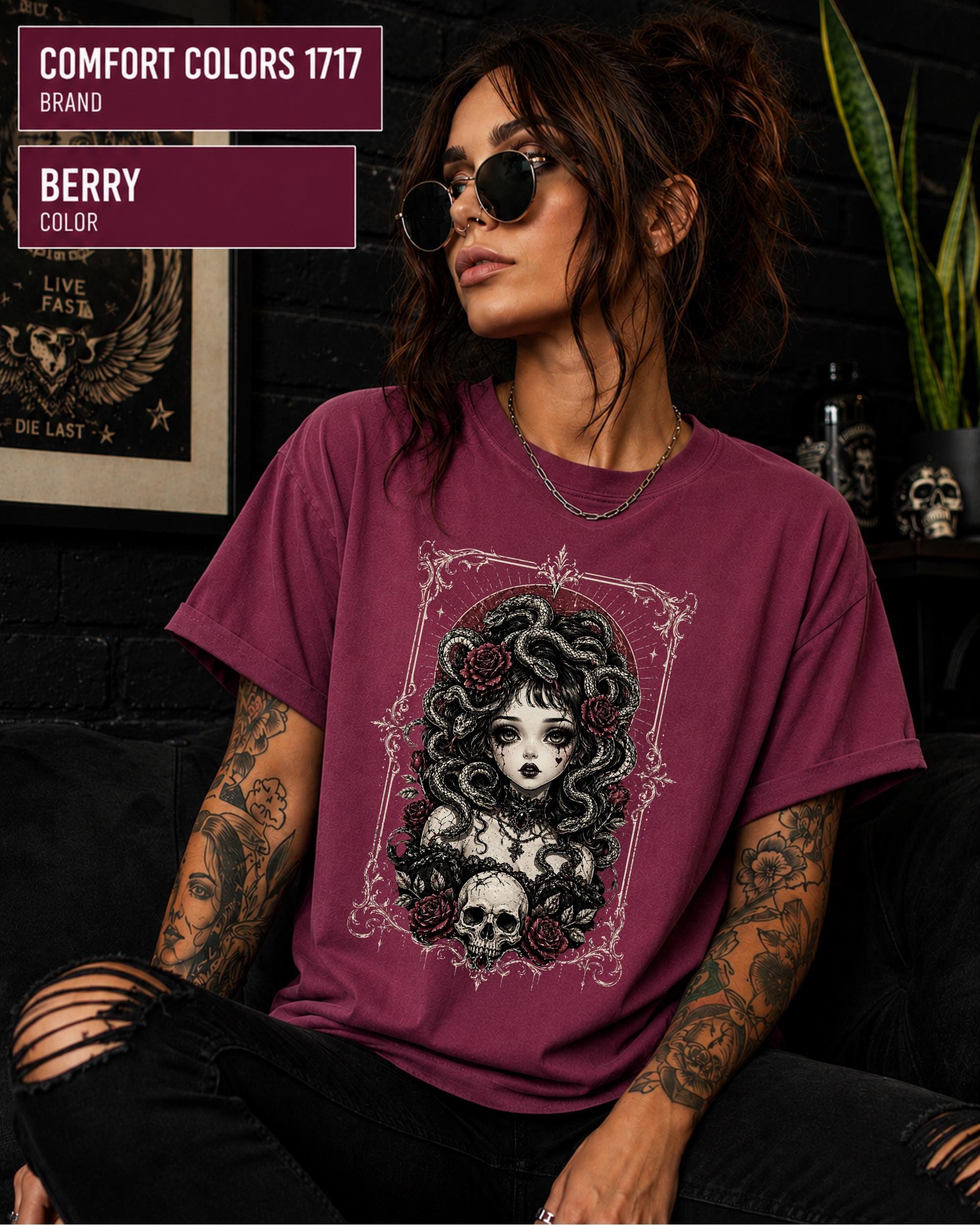Woman wearing a Berry Comfort Colors 1717 T-shirt featuring a gothic Medusa-inspired woman with snakes, dark roses, ornate framing, and a skull design.