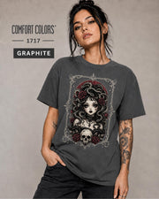 Woman wearing a Graphite Comfort Colors 1717 T-shirt featuring a gothic Medusa-inspired woman with snakes, dark roses, ornate framing, and a skull design.