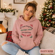 Female model wearing a dusty rose Christmas hoodie reading “If I had anymore Christmas spirit, I’d be shitting jingle bells” in a cozy holiday room.