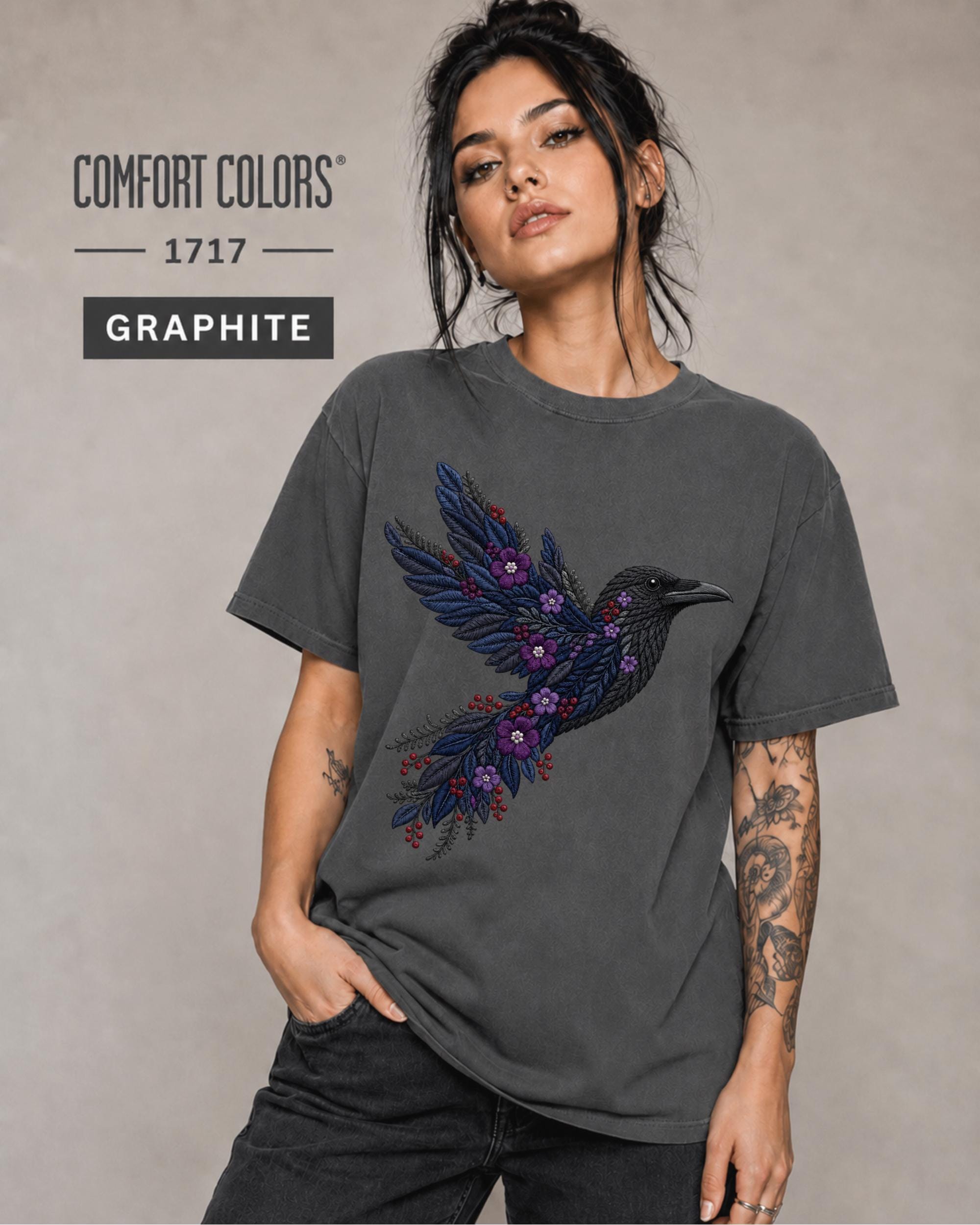 Graphite Comfort Colors 1717 t-shirt featuring a black raven graphic with purple flowers and blue feather details in a gothic botanical style.
