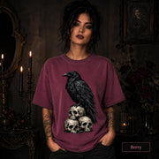 Dark academia shirt featuring a crow standing on a pile of vintage-style human skulls.