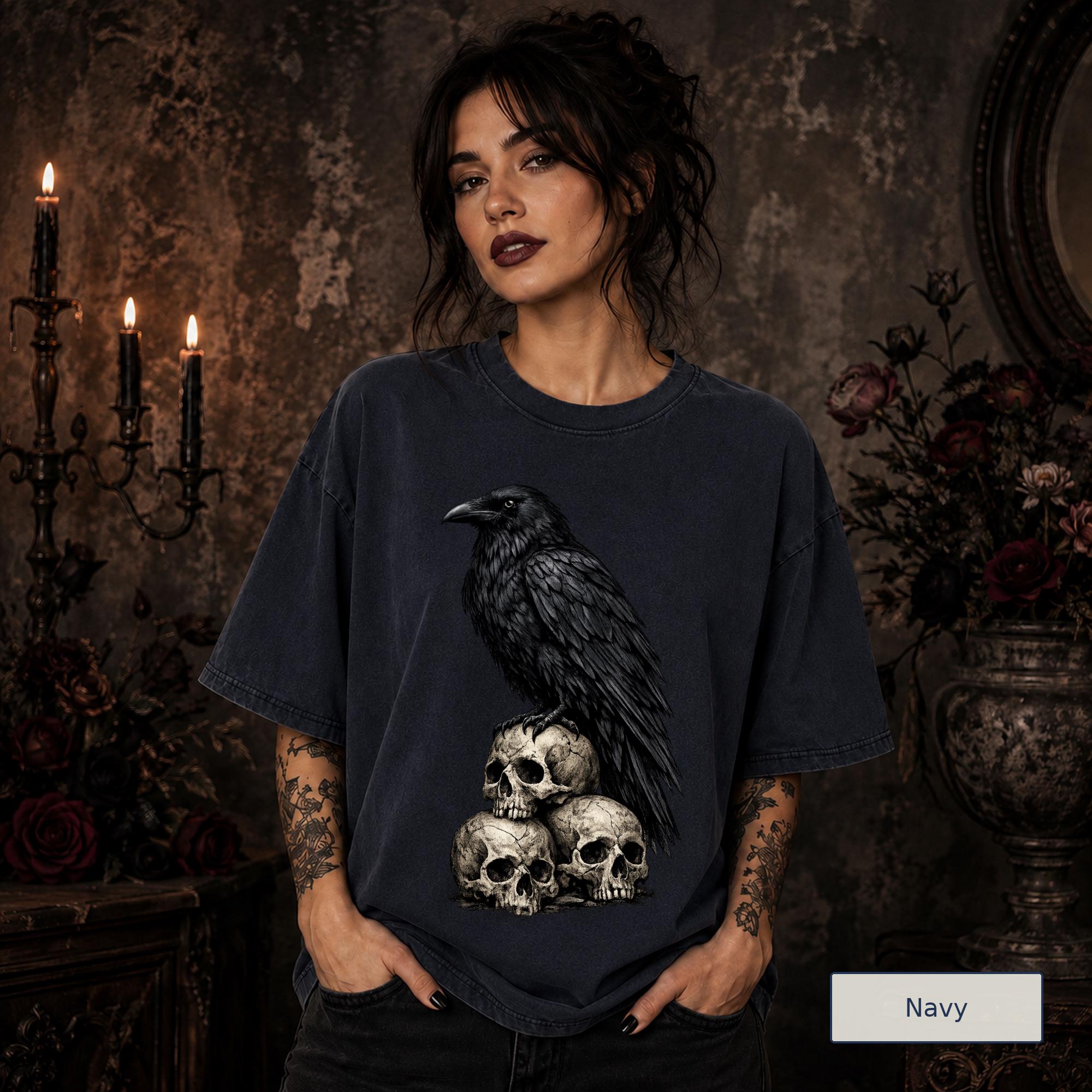 Gothic animal tee featuring a large black raven resting above three distressed skulls.