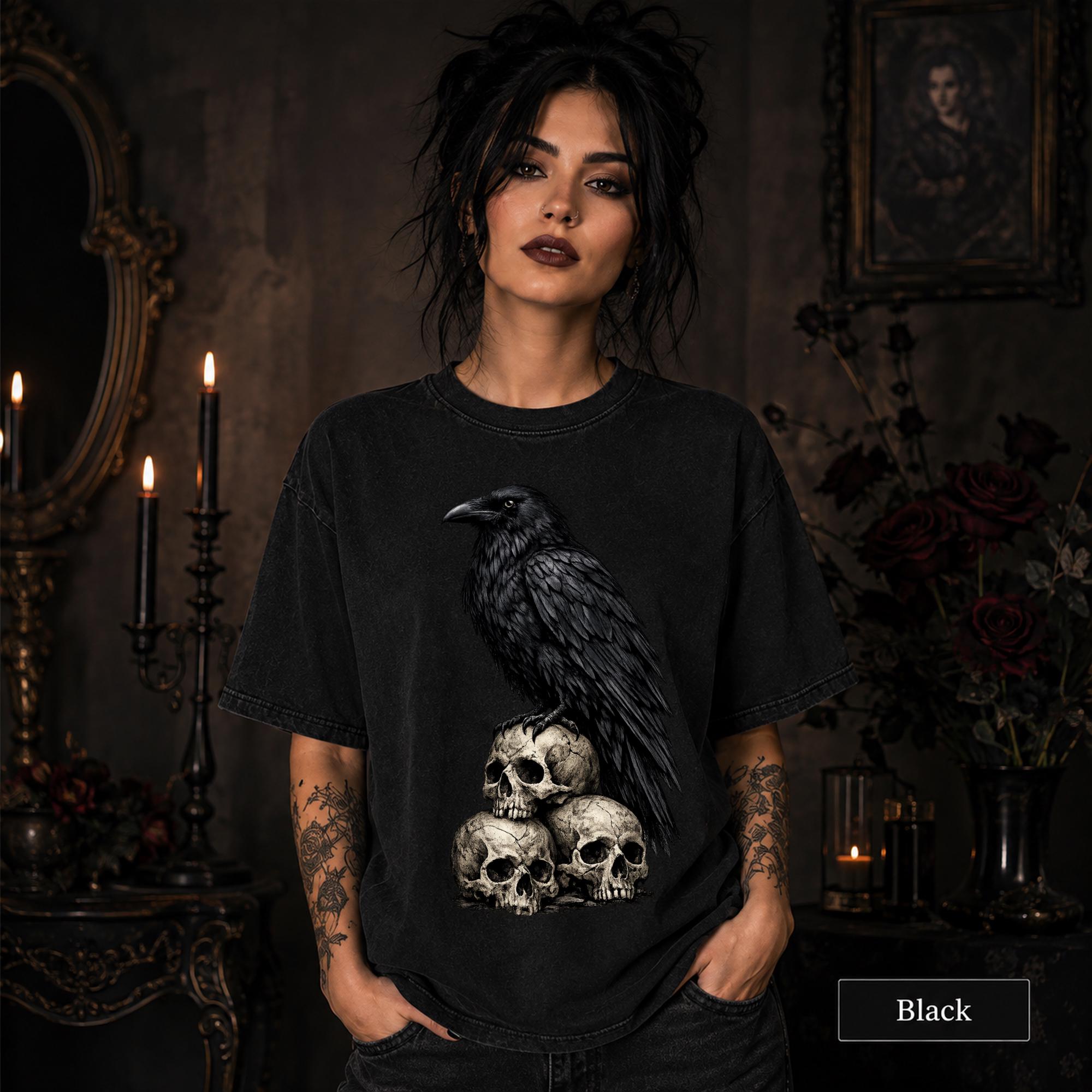 Woman wearing a Black Comfort Colors 1717 shirt featuring a black raven perched on three weathered skulls.