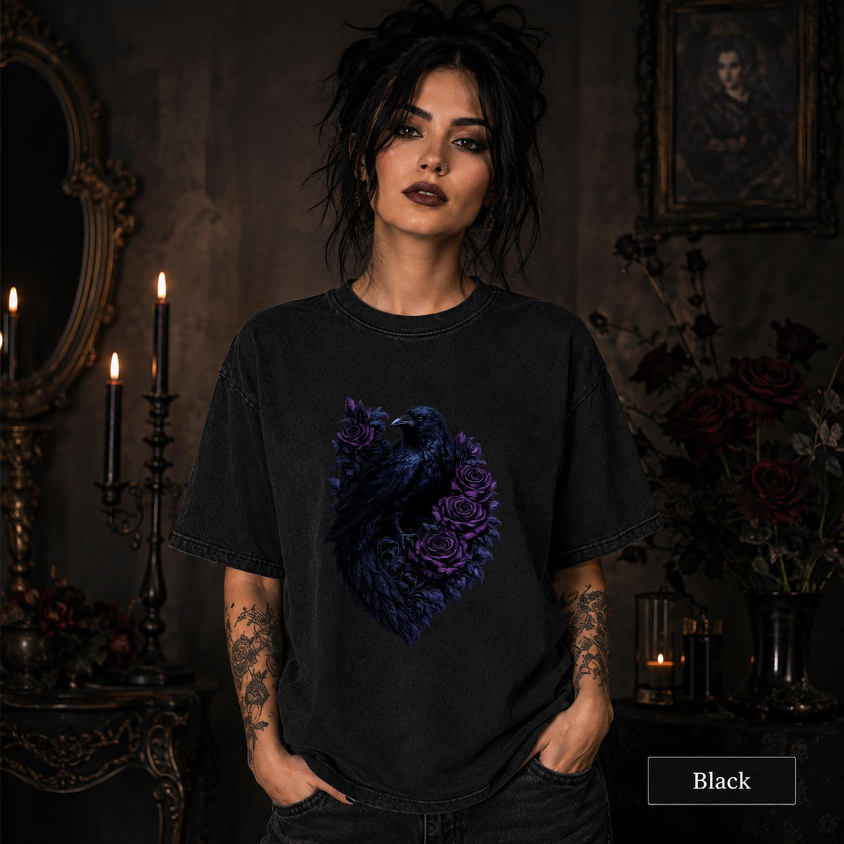 Woman wearing a black gothic raven T-shirt featuring deep purple roses in a dark candlelit room.