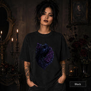 Woman wearing a black gothic raven T-shirt featuring deep purple roses in a dark candlelit room.