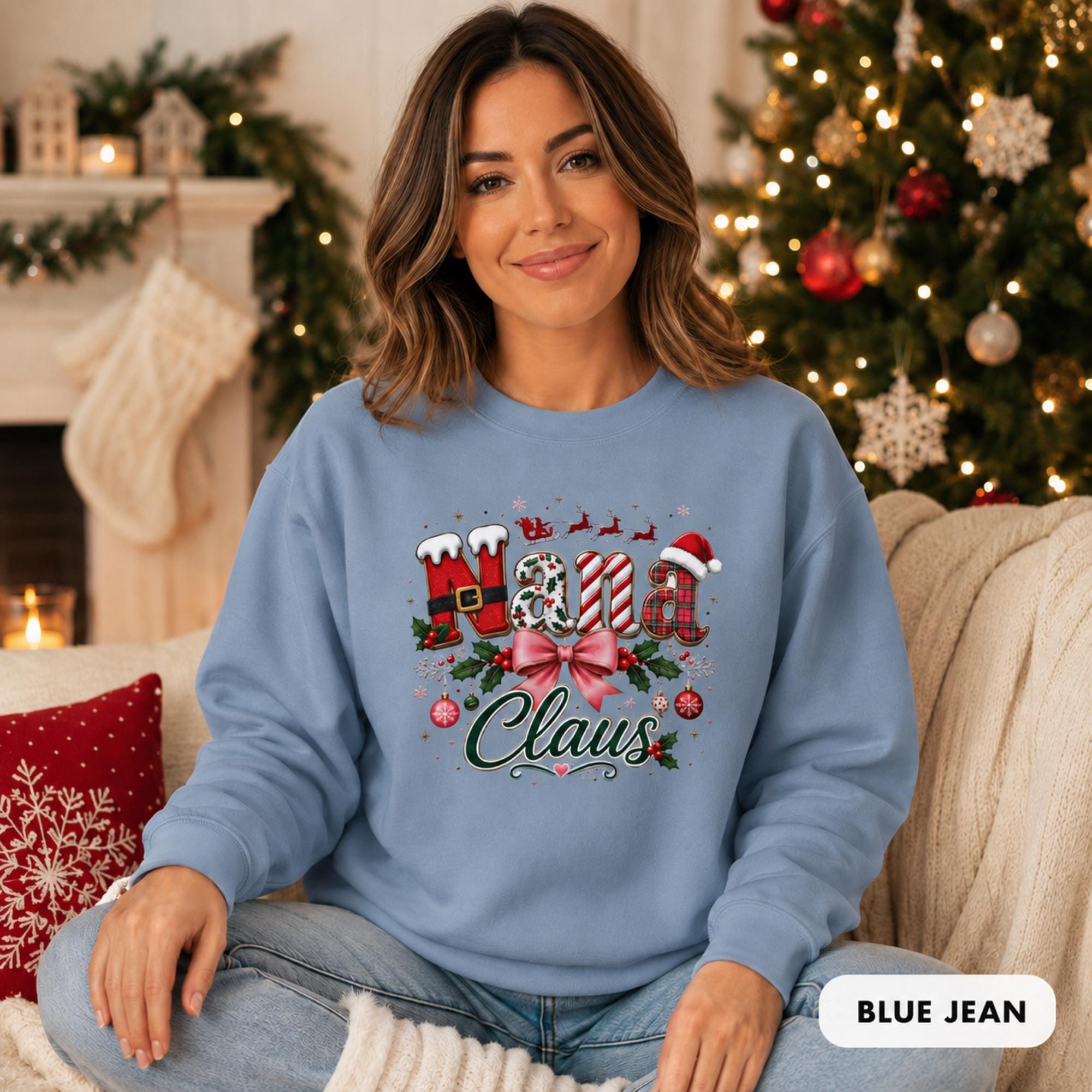 Female model wearing an blue jean Comfort Colors crewneck featuring a festive “Nana Claus” Christmas design with a pink bow, holly, ornaments, and holiday lettering.
